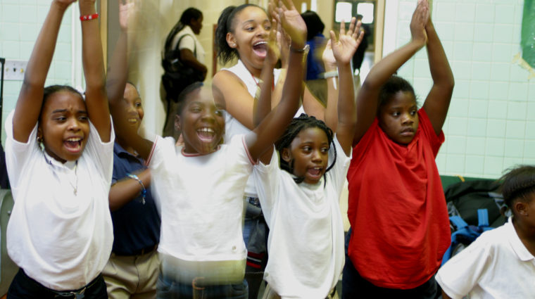 school children lined up in front of brick wall