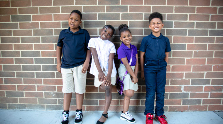 school children lined up in front of brick wall