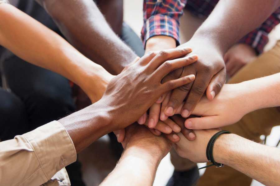 Diverse group puts hands in as a team