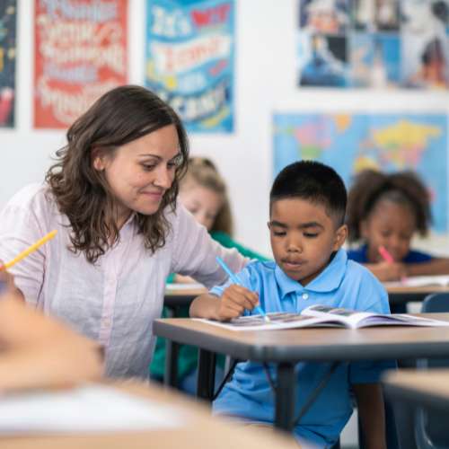 A teacher helps a young student