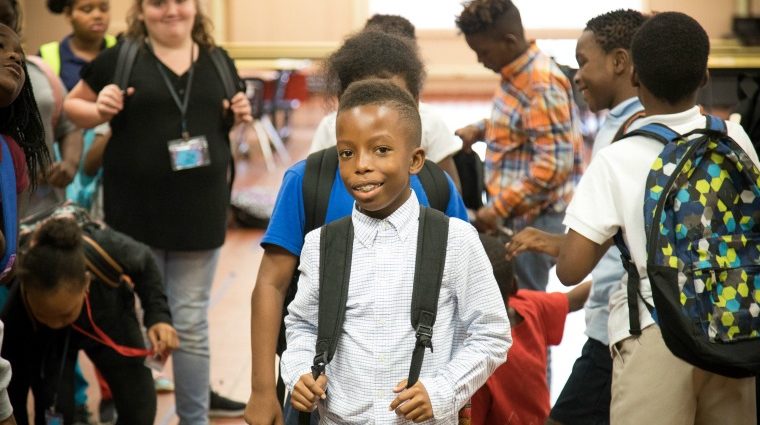 school children lined up in front of brick wall