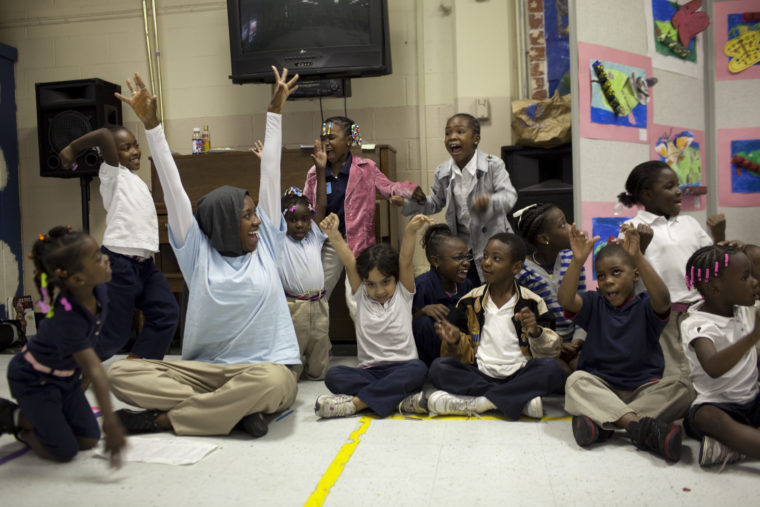 Student sitting in a circle raise their hands to show they are soaring