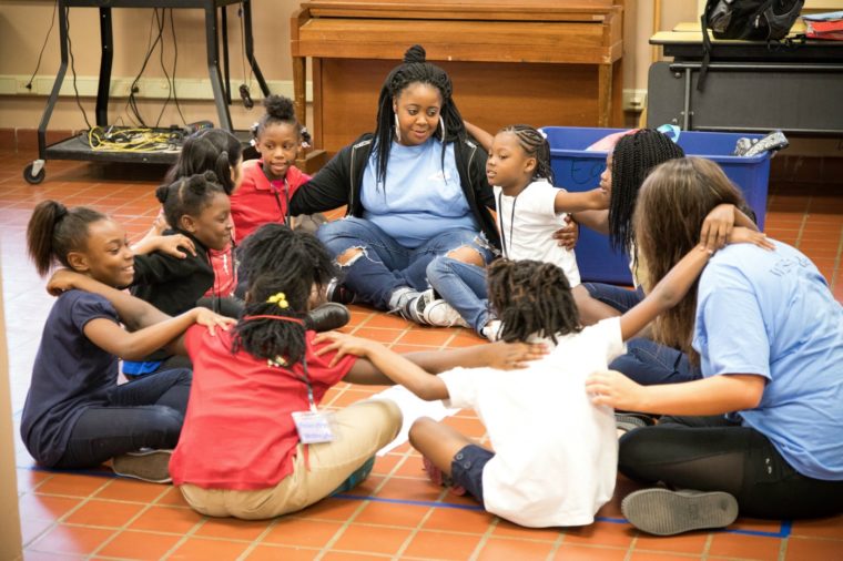 Students and staff are arm-in-arm in a circle